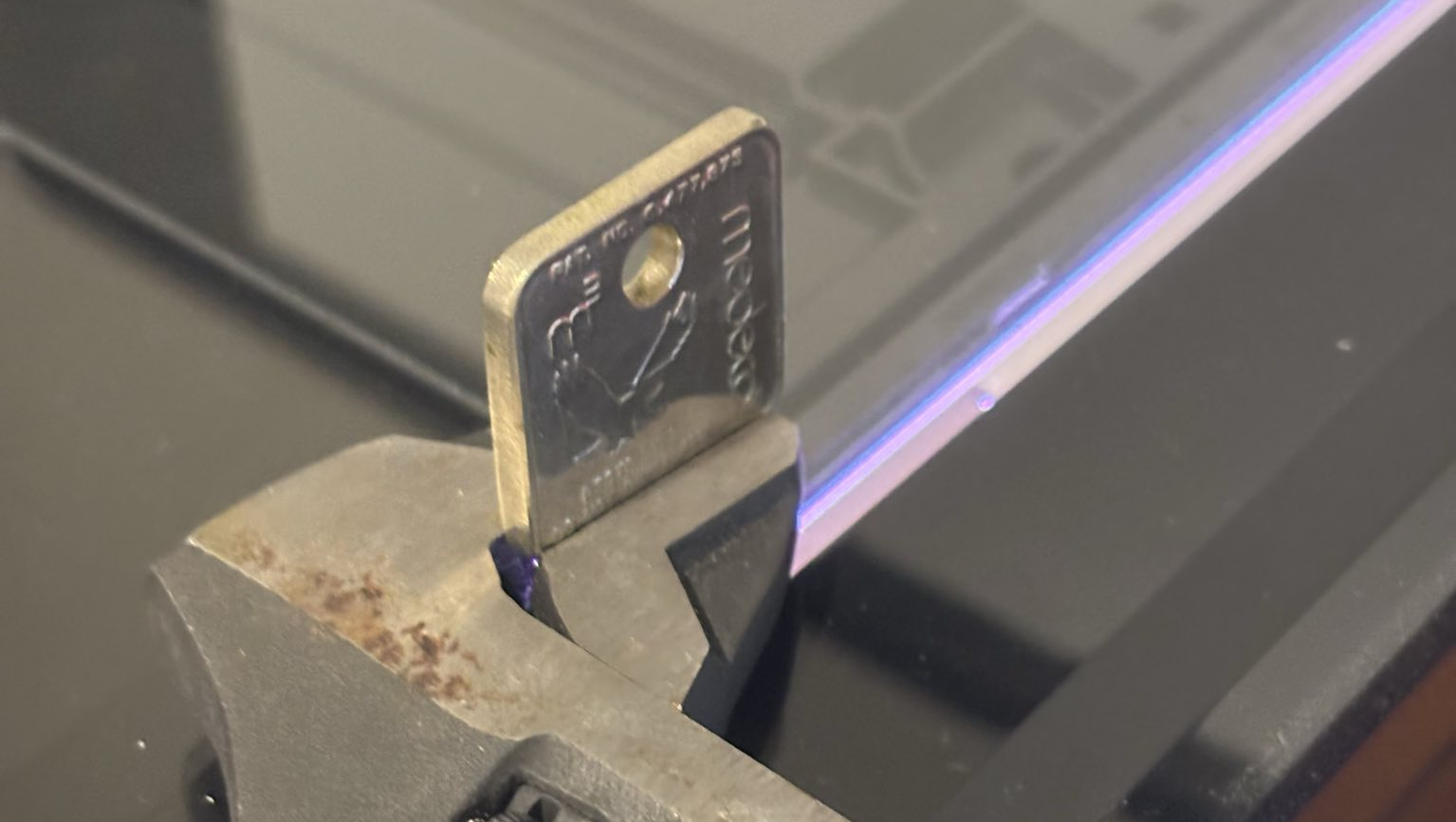 A photo of a key, with the blade ground off, held down onto a flatbed scanner with an adjustable wrench