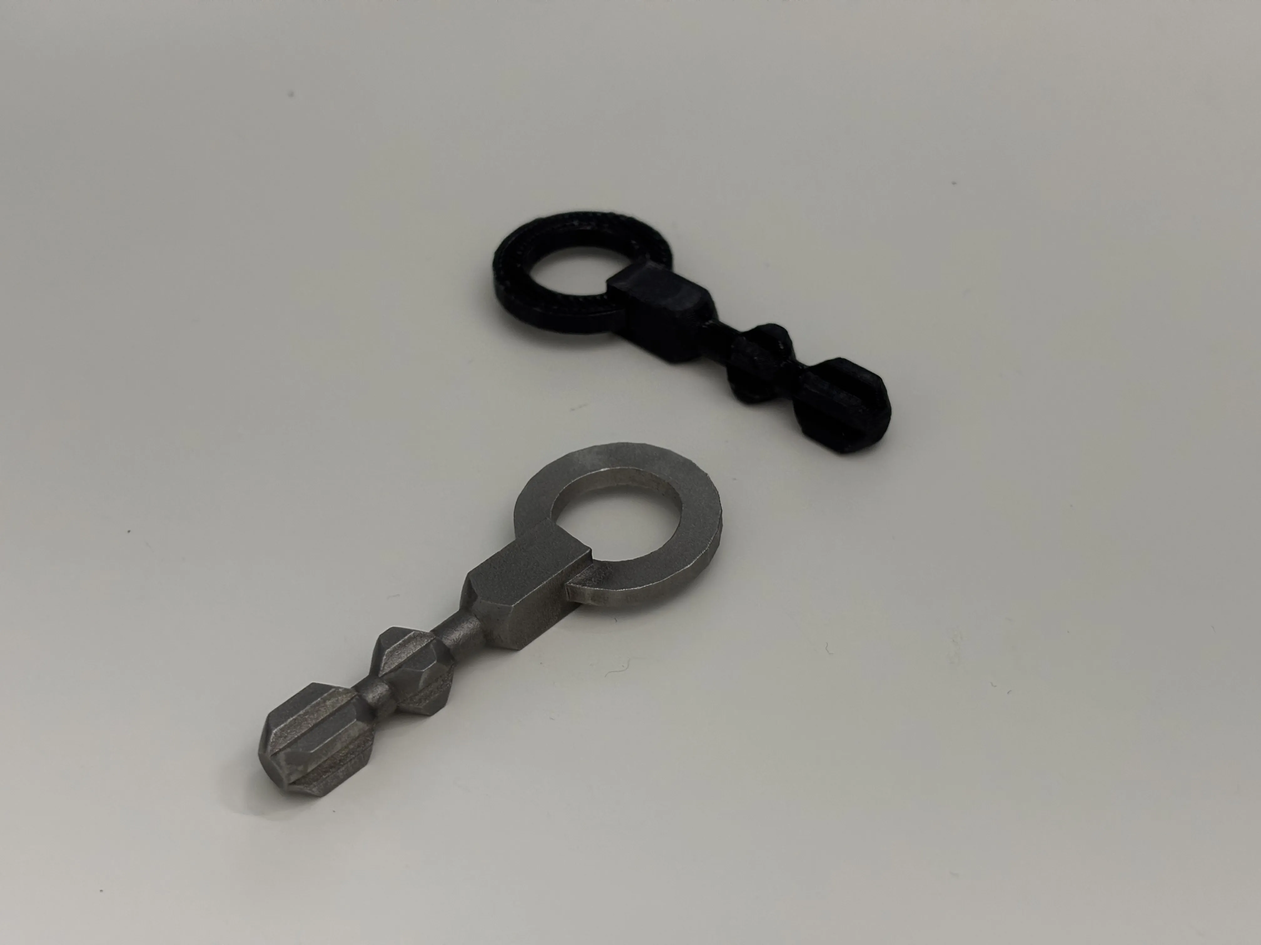 Photo of the 3D printed plastic prototype next to the metal final product. The metal has a dull finish